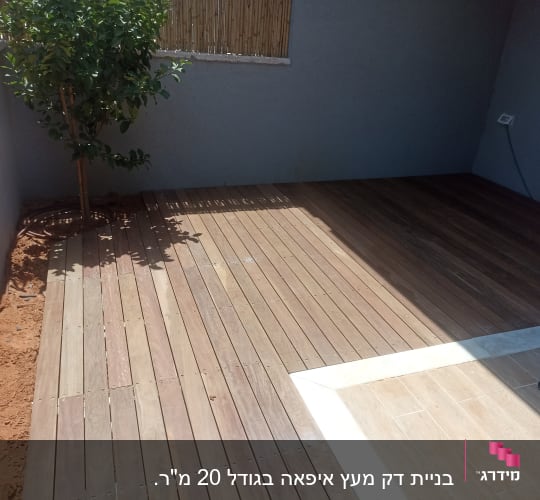 דק עץ בגינה עם עץ קטן בצד